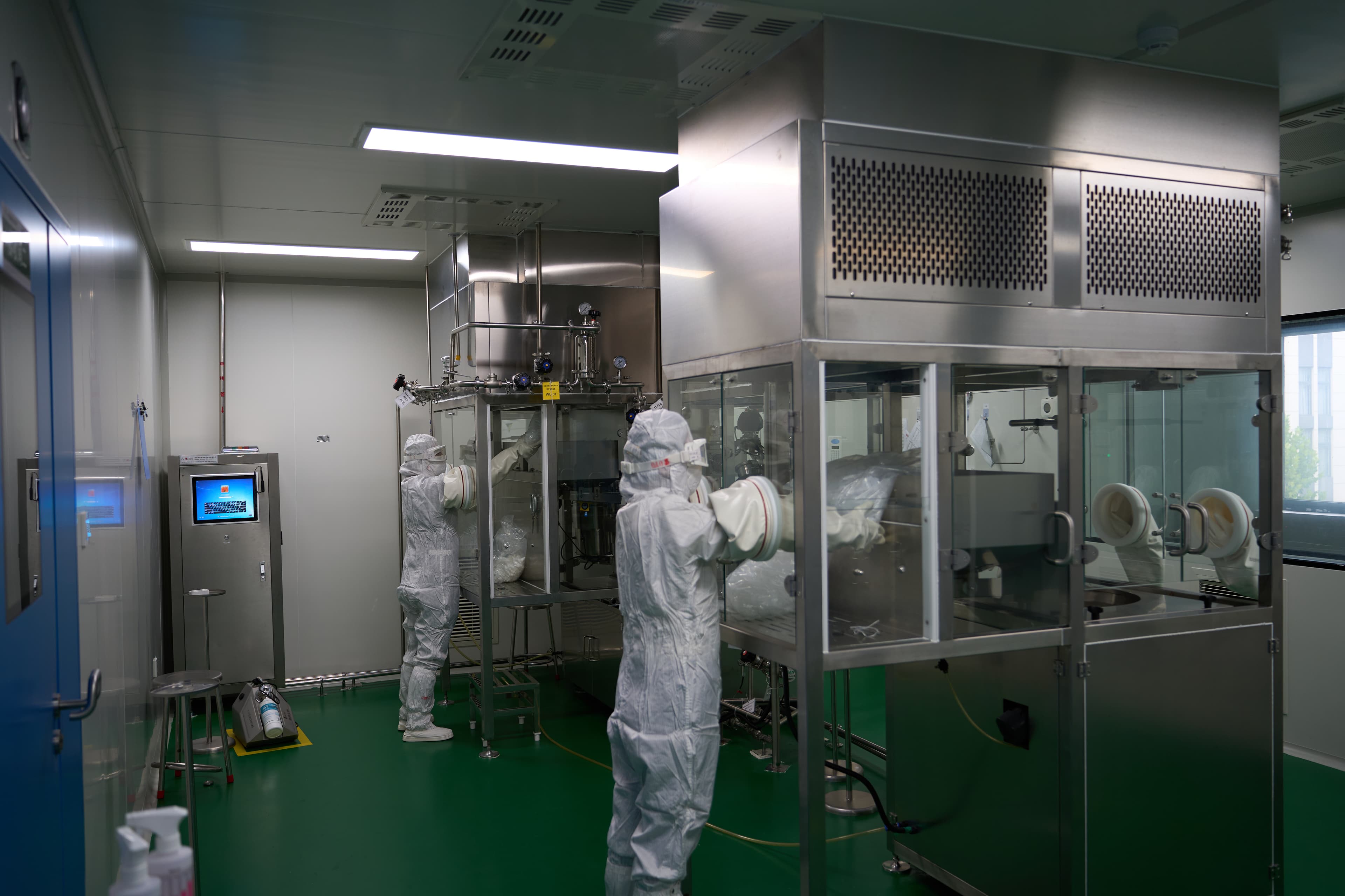 Cleanroom staff operating enclosed pharmaceutical production equipment